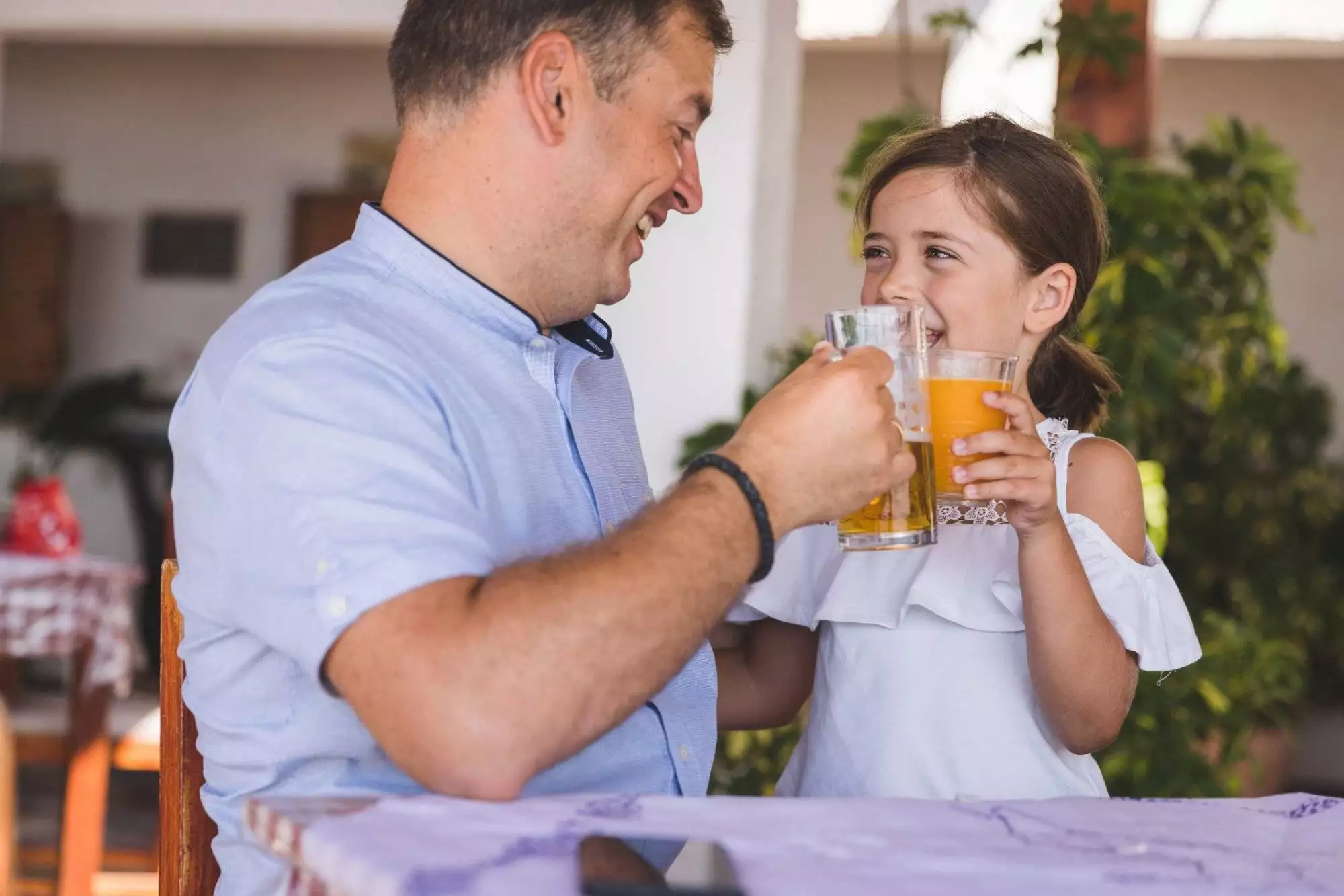 Happy man having a toast with his daughter drinking beer with him