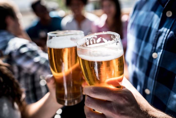 Close up of a customers at a bar holding a beer and making a toast